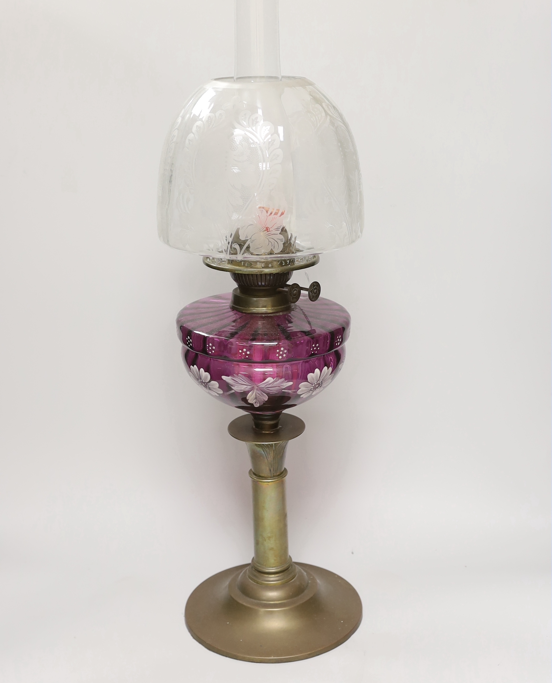 A Victorian oil lamp with an amethyst floral enamelled glass bowl and clear etched shade, 65cm high